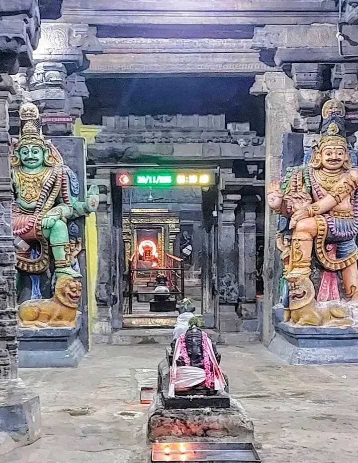 Brightly colored guardian sculptures (Dvarapalas) flanking the dark entrance to a temple inner sanctum