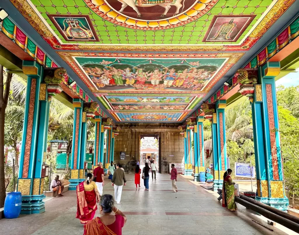 Decorated temple corridor with vibrant ceiling artwork and pillars Decorated temple corridor with vibrant ceiling artwork and pillars